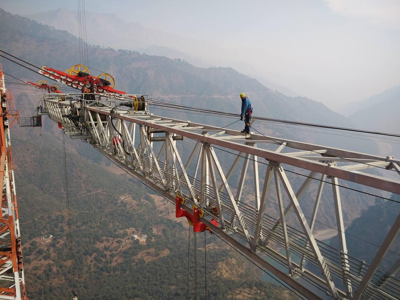 A crane over a bridge under construction in a mountain valley